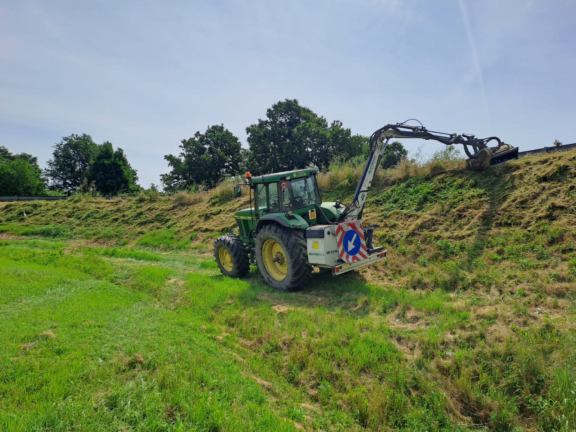Trattore con braccio escavatore su collina
